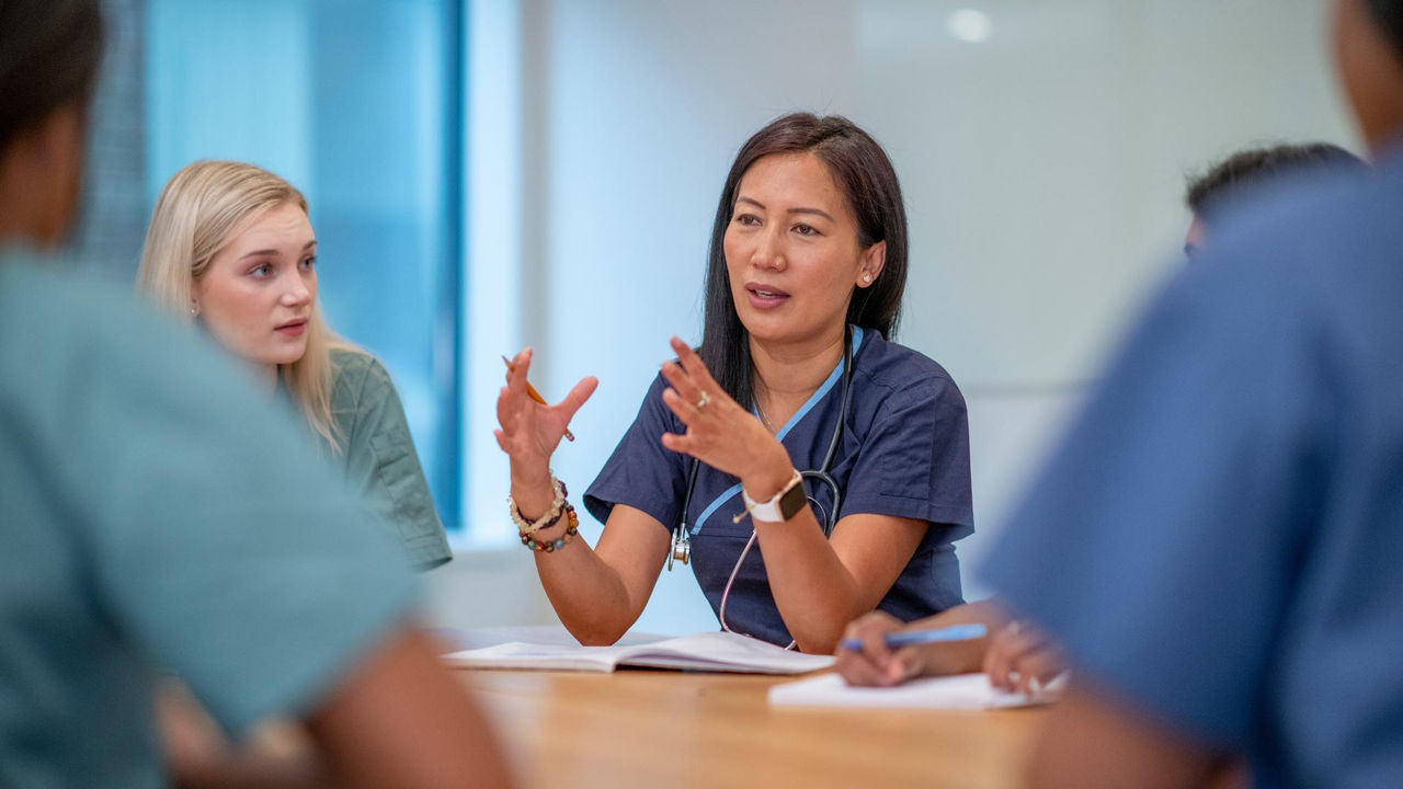 A Registered Nurse leads a meeting of healthcare professionals.