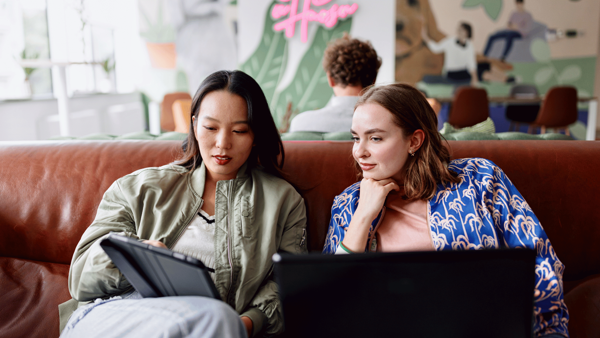 Two women comparing digital vs traditional marketing in a funky marketing office.