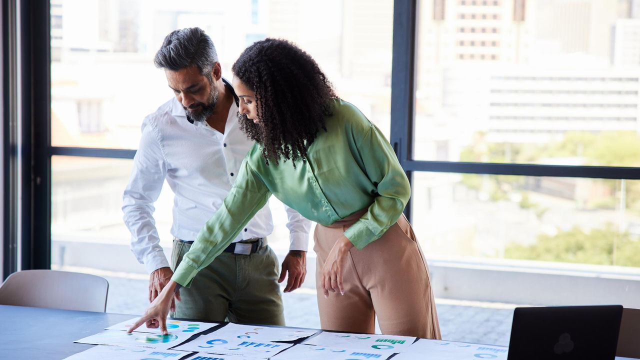 Two kaimahi | staff looking at industry training solution ideas for their team in a bright office.