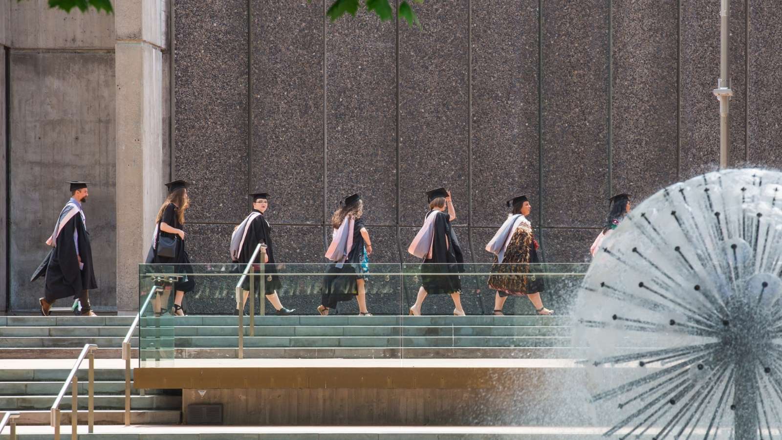 A professional woman greets UC Online team members before a meeting about staff training and development options.
