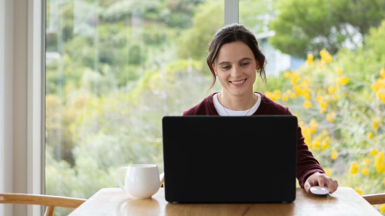 Woman studies online, smiling as she completes her coursework with UC Online
