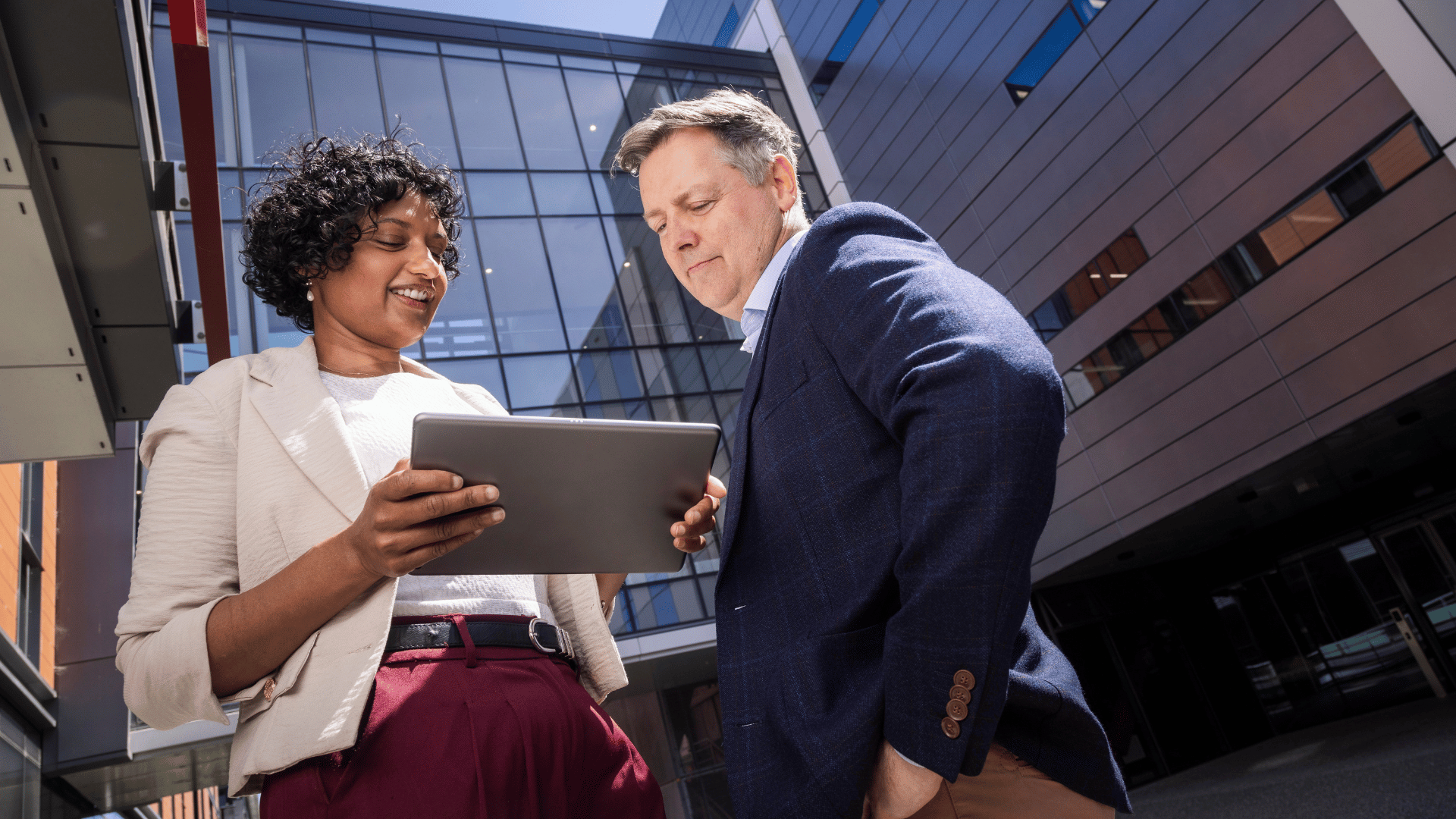 A female data science professional showing her colleague her progress in her online data science courses on her tablet. 