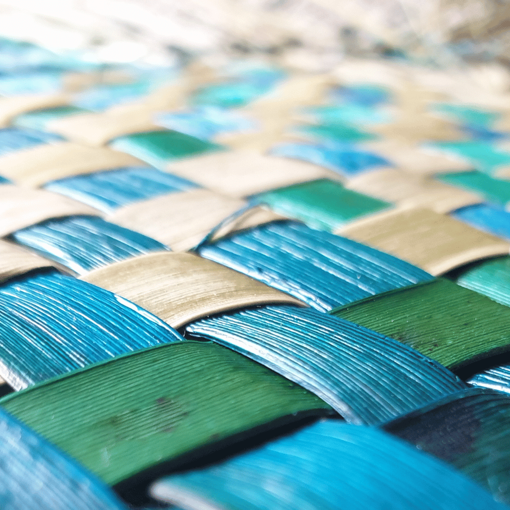 A close up image of woven harakeke in deep green and blue colours