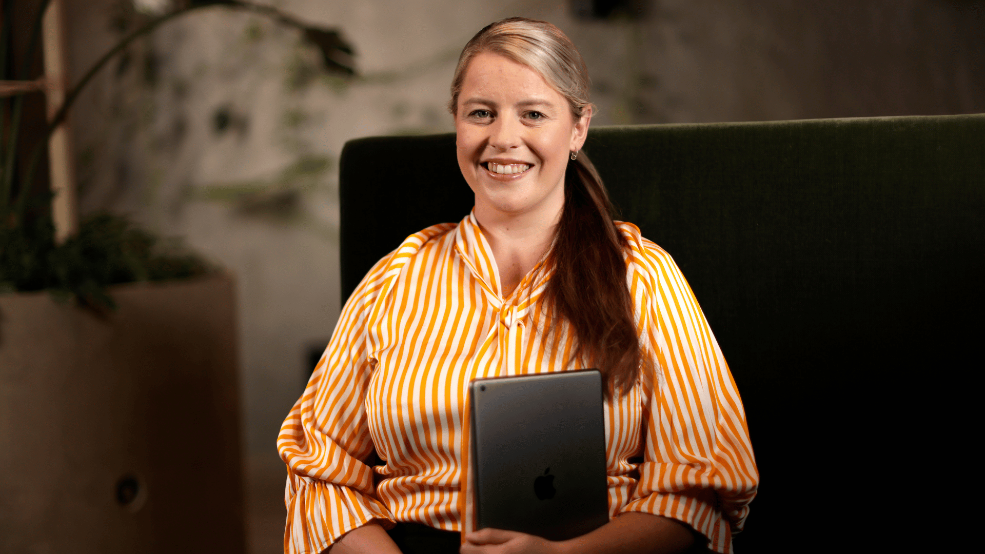 A criminal justice professional smiling in a yellow shirt as she talks to her colleagues about her online criminal justice course
