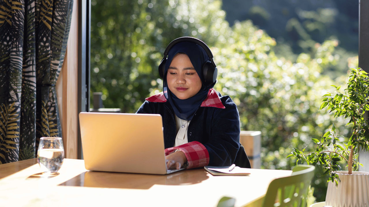 Student studying in a library, joining a video session for her online Bachelor of Health, Health Science course