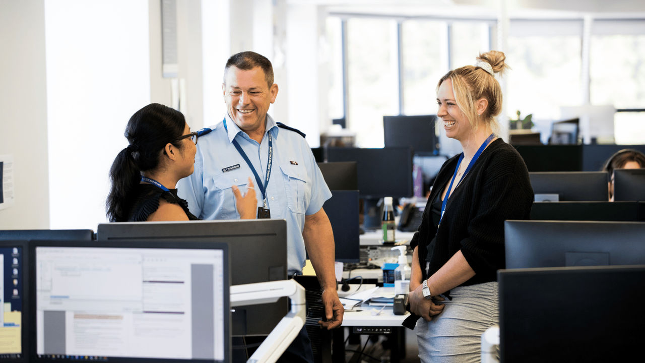 Two UC Online Certificate in Criminal Justice students discuss the course material with a smiling New Zealand Police officer.