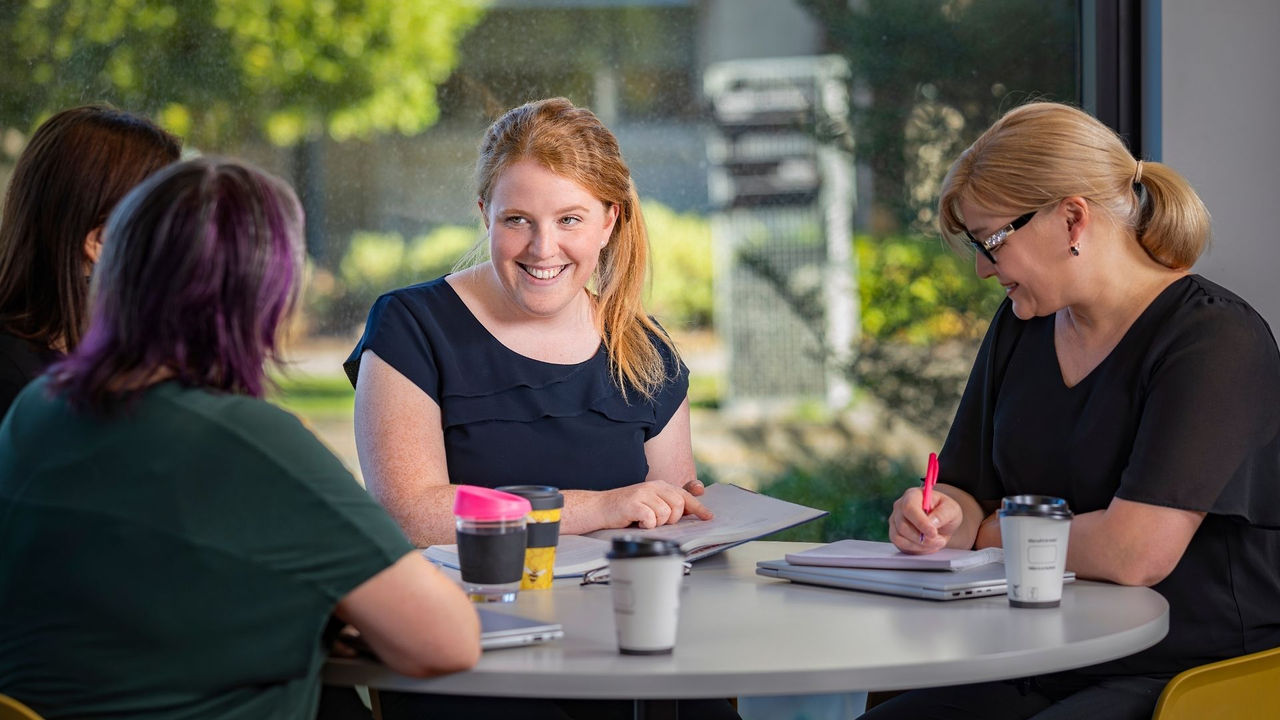Healthcare professionals in discussion, with one woman presenting her project from a Master of Business Administration in Health programme.