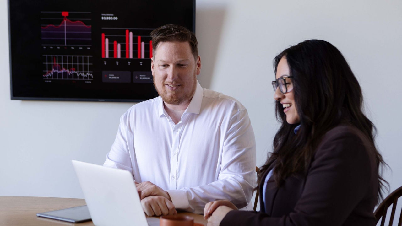 Two business professionals meeting with a laptop, representing learners in an online Postgraduate Diploma in Business Administration