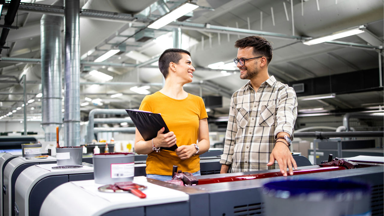 A UC Online student, working in an industrial warehouse, discusses the Master of Engineering Management with a colleague.