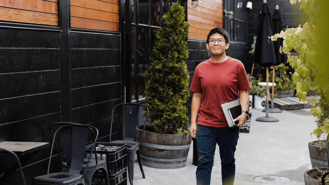 Young physio in red shirt walks outside on his way to study his postgraduate certificate in clinical exercise physiology