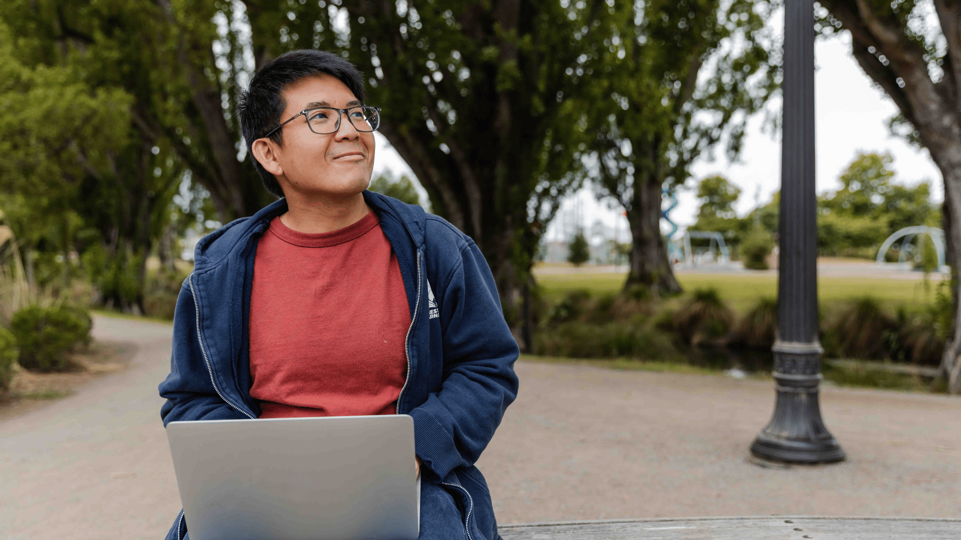 Male learner sitting outside on his laptop, considering online study with UC Online