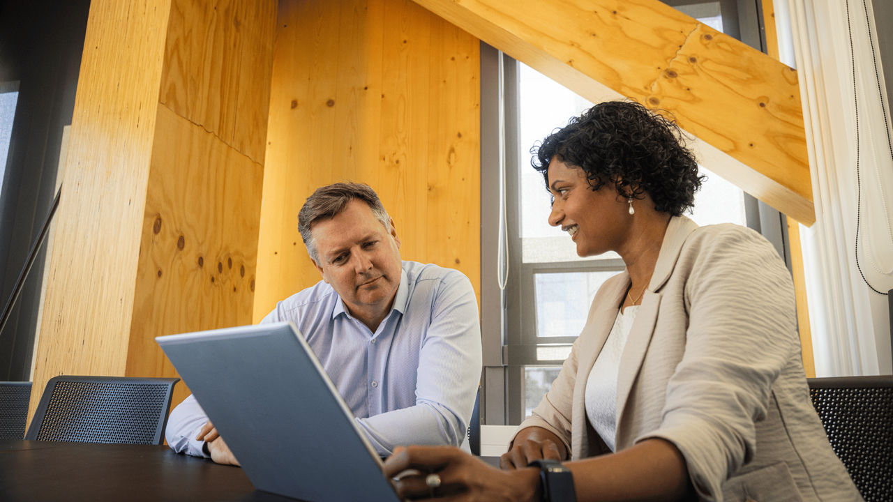 Two people working at a desk, smiling