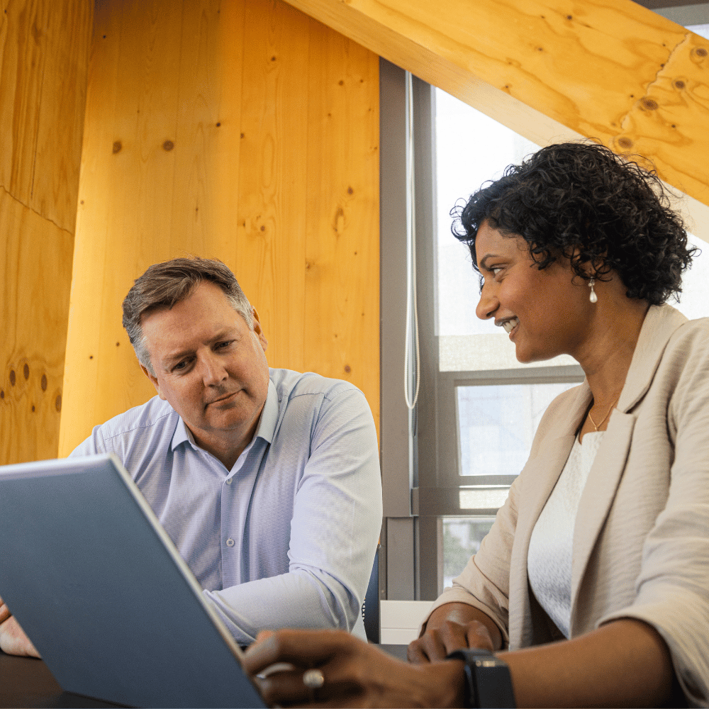 Two people working at a desk, smiling. 