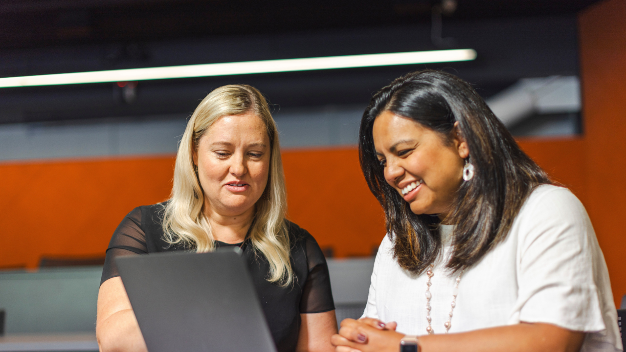 Two female teachers looking at a laptop discussing how to design authentic assessment in the age of AI