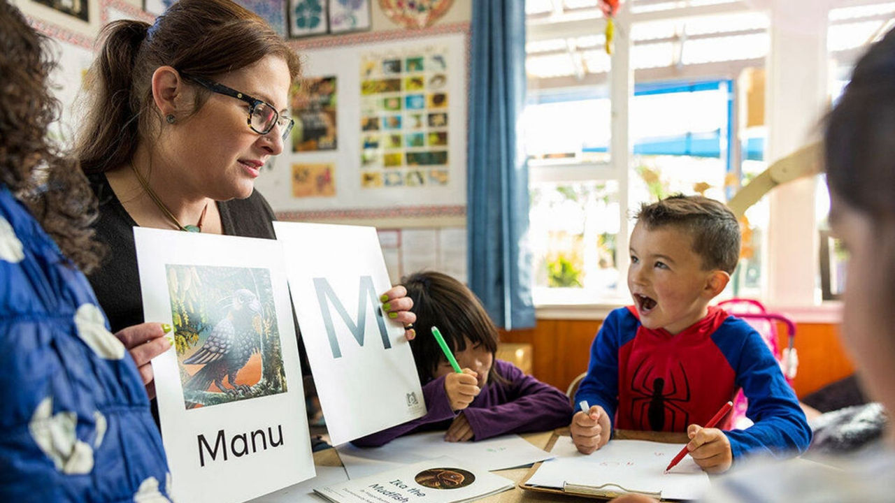 Teacher reading to children in a classroom, using structured literacy techniques learnt from her online literacy degree