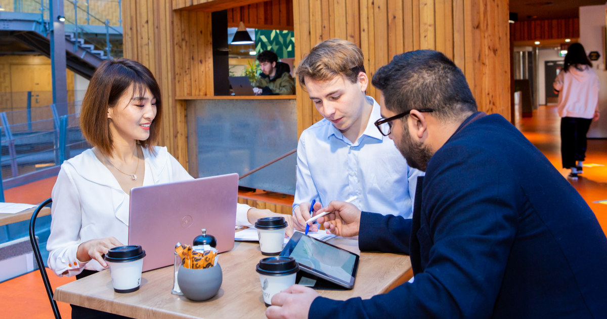 Three people looking at screens around a table in a university building-instructional-design-development